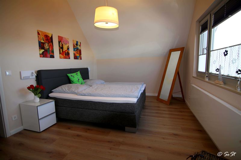 Schlafzimmer mit Doppelbett und bunten Bildern