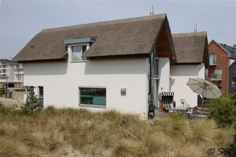 Seitenansicht des Reetdachhauses mit Terrasse und Dünengras