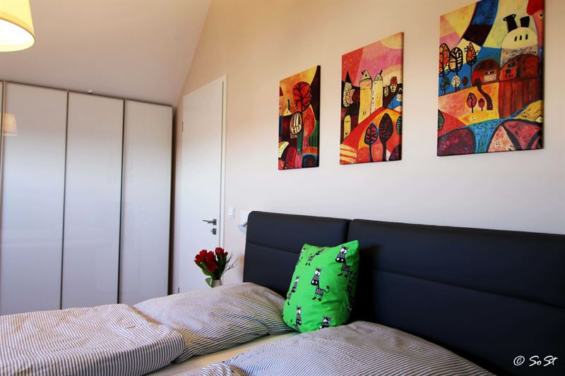 Schlafzimmer mit dunklem Bett und bunten Bildern