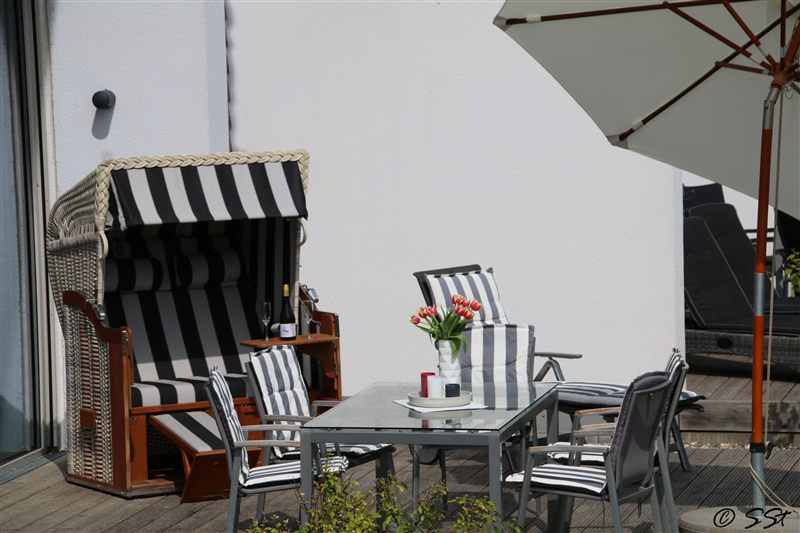 Terrassentisch mit Tulpen, Strandkorb und Sonnenschirm